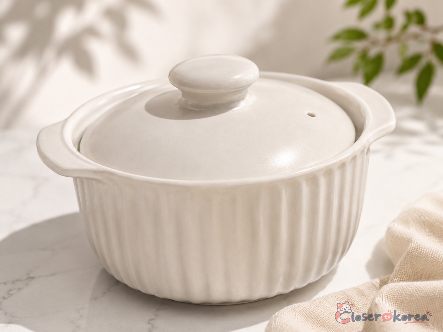 White ceramic Korean microwave steamed egg cooker with lid and side handles on a light marble surface